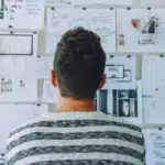The back of a person looking at a bulletin board densely covered with papers and notes, symbolizing the overwhelming feeling of managing numerous IEP meetings and speech therapy goals.