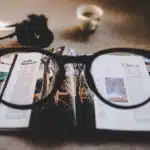 Photograph of a pair of eyeglasses resting on an open book displaying various pictures, symbolizing the use of visual aids in therapy and learning.