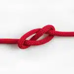 A red cord with a tight knot, symbolizing the restricted tongue movement associated with tongue tie.