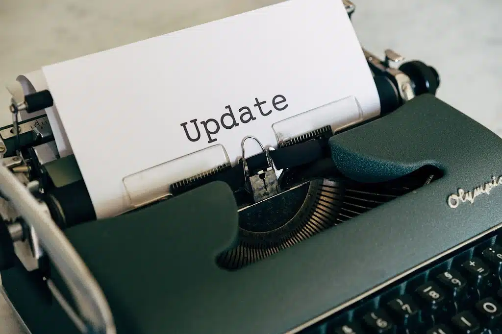 A close-up of a vintage green typewriter with a piece of paper inserted, on which the word "Update" is clearly typed in black.