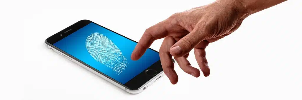 A hand reaching towards a smartphone screen that displays a prominent blue fingerprint graphic, indicating biometric security or digital access.