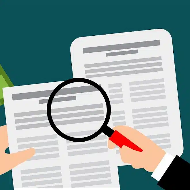 Illustration of hands holding a document, with a magnifying glass examining text, symbolizing due diligence and review of Business Associate Agreement terms.