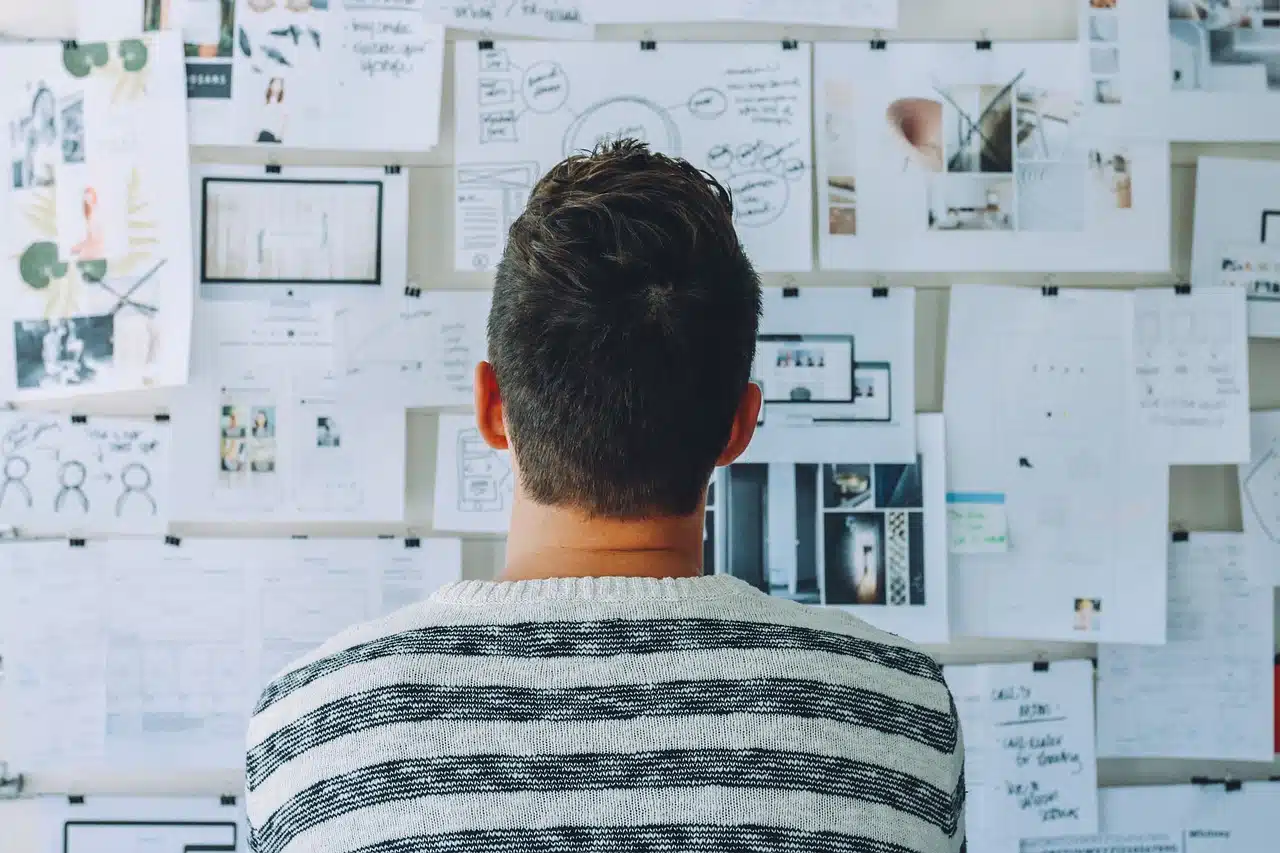 The back of a person looking at a bulletin board densely covered with papers and notes, symbolizing the overwhelming feeling of managing numerous IEP meetings and speech therapy goals.