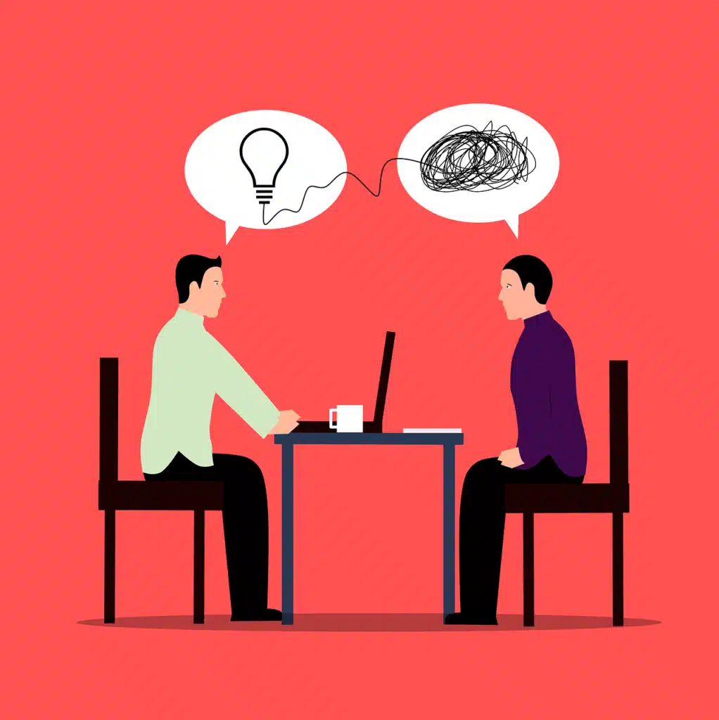An illustration of two people facing each other across a table with a laptop, one with a lightbulb thought bubble and the other with a tangled scribble, representing communication difficulties and the journey of understanding.