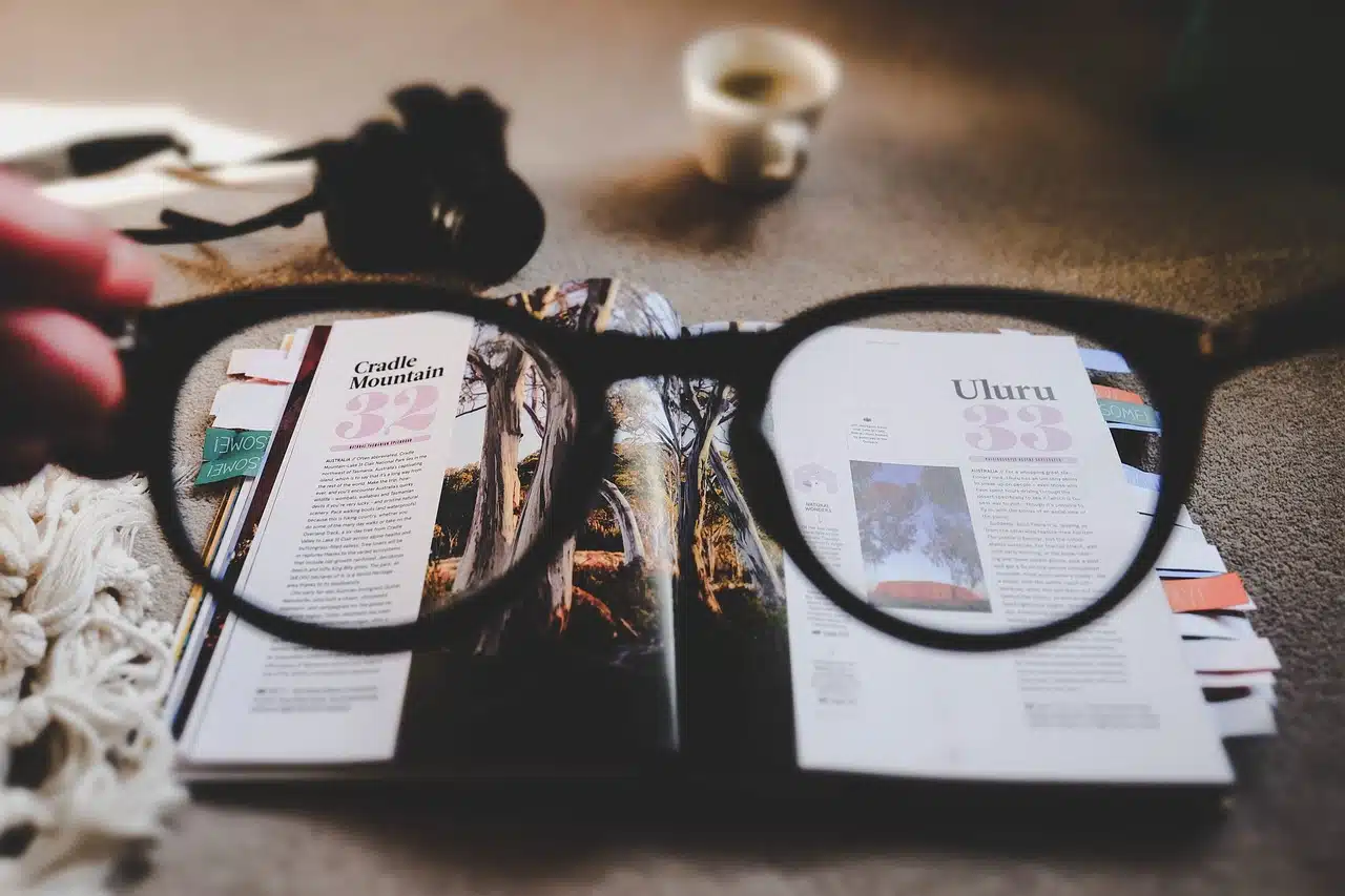 Photograph of a pair of eyeglasses resting on an open book displaying various pictures, symbolizing the use of visual aids in therapy and learning.