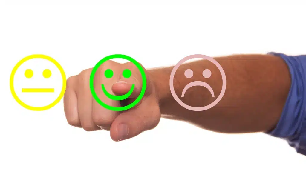 Hand choosing between sad, happy or neutral emoticons, symbolizing  student check-ins.