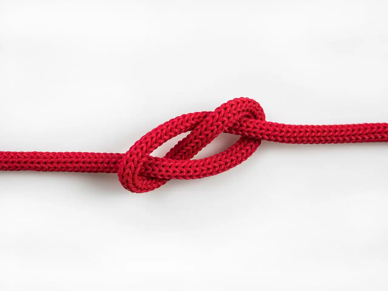 A red cord with a tight knot, symbolizing the restricted tongue movement associated with tongue tie.