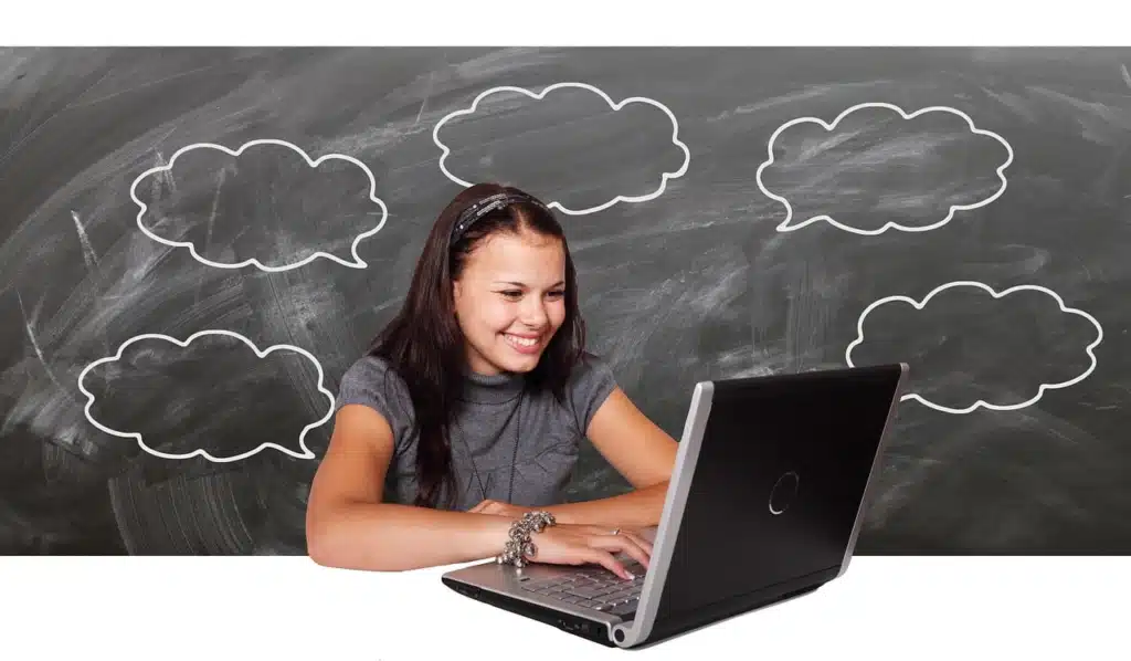 A smiling girl sitting at a laptop, with several empty thought bubbles floating above her head.